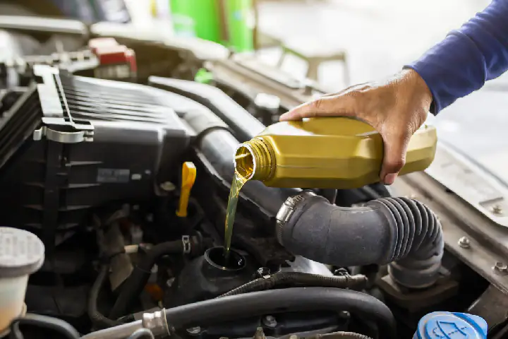 Mechanik warsztatu LCL Car service wlewa olej silnikowy do samochodu