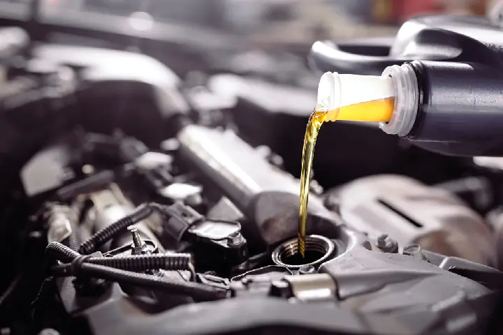 Wlewanie oleju silnikowego do samochodu podczas wizyty u mechanika